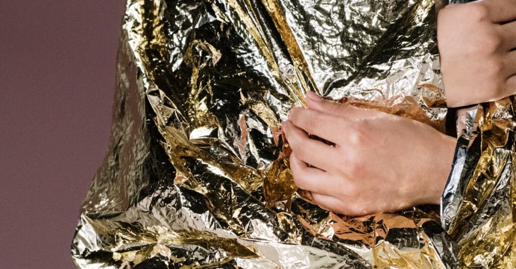 Close-up of a person wrapped in a reflective emergency blanket for warmth and protection.
